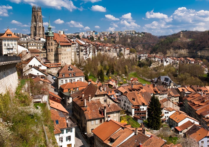 Photo of historic old town of Fribourg in Switzerland with the church of St. Nicholas and historic houses in fine weather.