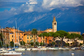 Photo of Old harbour Porto Vecchio with motor boats on turquoise water, green trees and traditional buildings in historical centre of Desenzano del Garda town, Northern Italy.