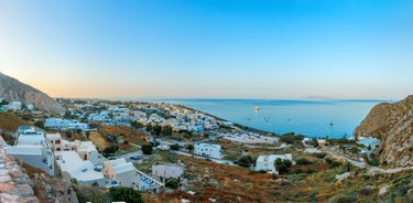 Photo of aerial view of black Perissa beach with beautiful turquoise water, sea waves and straw umbrellas, Greece.