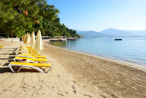 Photo of beautiful beach with sunbeds and umbrellas on turkish resort, Fethiye, Turkey.