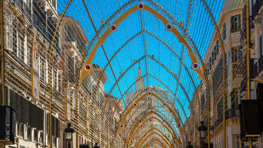 A street scene on Calle Larios, adorned with illuminated arches and intricate lights stretching across the sky between tall buildings..jpg