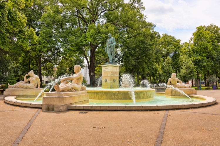 Photo of the "Bruat Fountain" with its sandstone figures and a bronze statue of Admiral Bruat on Mars field in the French city of Colmar in Alsace.