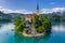  Aerial view of beautiful Pilgrimage Church of the Assumption of Maria on a small island at Lake Bled (Blejsko Jezero) and lots of Pletna boats on the lake at summer time with blue sky