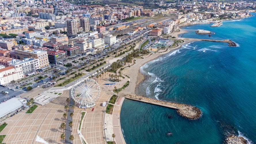 Aerial view of the Ferris wheel located on the waterfront of Civitavecchia in the Metropolitan City of Rome, Italy. On the city's waterfront there is a park, residential buildings and an empty beach.