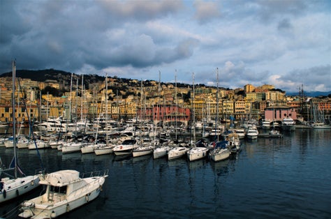 PHOTO OF Beautiful scene of the port of Genoa with lined boats berthed at the pier in a cloudy day. Point of view from the aquarium.