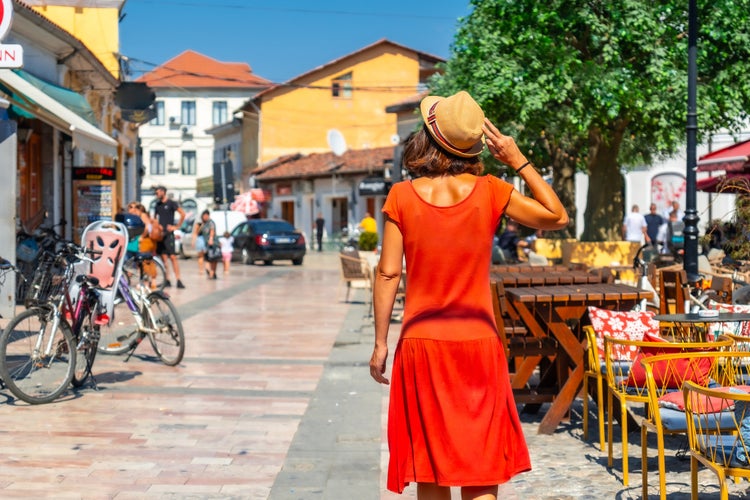 photo of Tourist woman in red dress and hat enjoying vacation walking on the streets of Shkoder city. Albania.