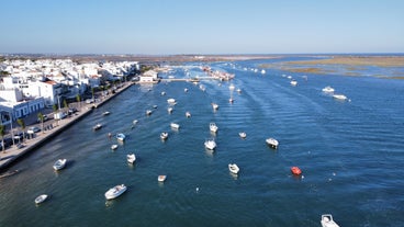 Photo of aerial cityscape of beautiful Tavira with roman bridge over Gilao river in the evening, Algarve, Portugal.