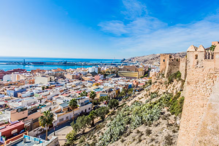 The aerial view of Almeria, Spain, showcases the city-s urban landscape, coastline, and historic Alcazaba fortress with clear blue skies..png