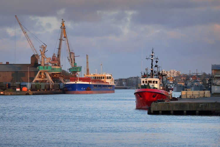 photo of view of anchored in a trading port. Cranes in the background. Liepaja, Latvia, Baltic sea. Freight transportation, logistics, global communications, industry, economy