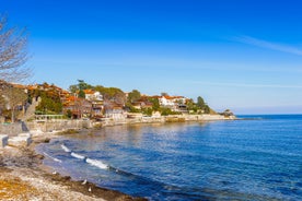 Photo of Saint Anastasia Island in Burgas bay, Black Sea, Bulgaria. Lighthouse tower and old wooden buildings on rocky coast.