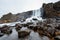 photo of the beautiful oxarárfoss waterfall flows from the river oxará over black basalt rocks into the almannagjá gorge, Þingvellir, Thingvellir national park, Golden circle route, Iceland.