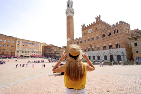 photo of holidays in Tuscany. Back view of beautiful woman visiting main square of Siena, Italy.