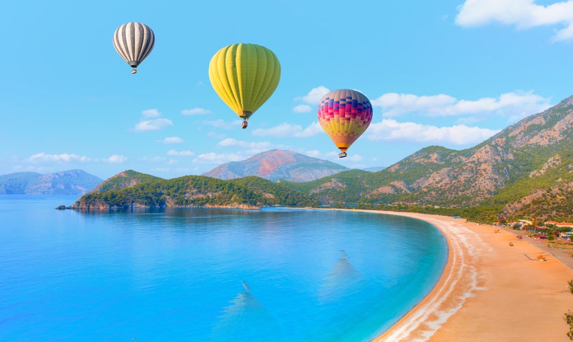 Photo of hot air balloon flying over spectacular oludeniz (ölüdeniz) lagoon and beach in Fethiye, Turkey.