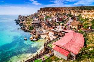 Photo of aerial view of seaside cliffs, colourful houses and streets of Qawra town in St. Paul's Bay area in the Northern Region, Malta.