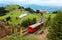 photo of sightseeing train traveling on the cogwheel railway through green grassy meadows on Rigi Kulm Mt. Rigi, with rugged Pilatus peaks among majestic mountains in background on a cloudy summer day in Switzerland.