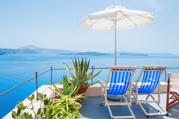 Photo of sunbeds looking to the amazing view of Santorini, Greece.