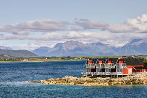 photo of view of Entrance from sea into fishing village of Stokmarknes, Norway, with mountains behind.