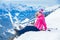 photo of  view of Young girl with her mother in a ski outfit sitting on the snowy hill in the Zillertal Arena, Austria,Radstadt Austria.