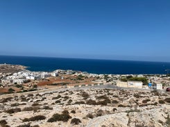 Photo of aerial view of seaside cliffs, colourful houses and streets of Qawra town in St. Paul's Bay area in the Northern Region, Malta.