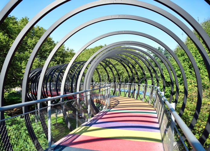 Photo of Slinky Springs Bridge at Oberhausen Kaisergarten,. Abstract bridge with metal rings and multicolored floor. Sunny day at Kaisergarten, Oberhausen, Germany.