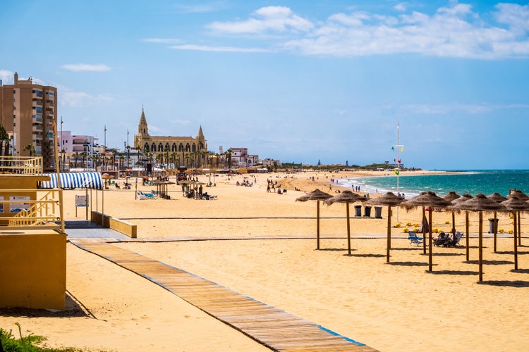 Photo of great view of Chipiona beach in Cadiz province, blue sky, white sand, palm trees, Spain.