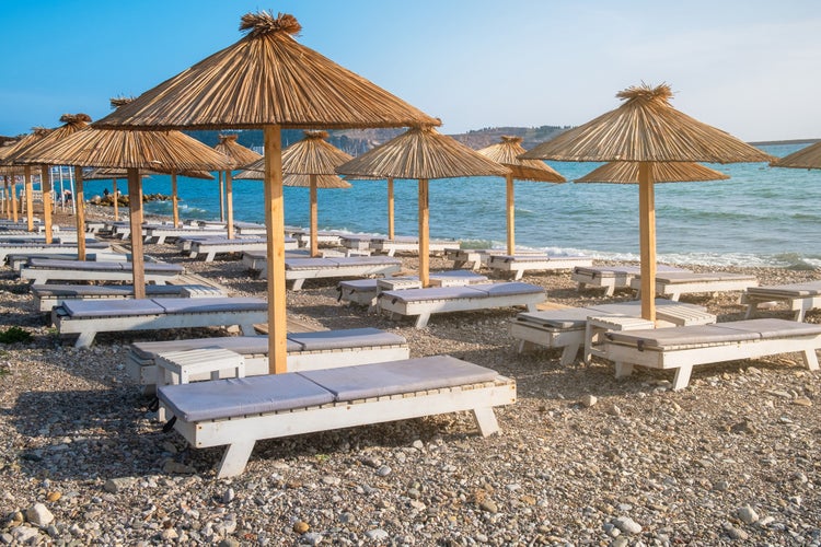 Photo of beach with sun umbrellas and sunbeds in town Bar in Montenegro on Adriatic sea.