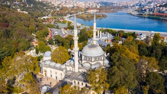 Touristic sightseeing ships in Golden Horn bay of Istanbul and mosque with Sultanahmet district against blue sky and clouds. Istanbul, Turkey during sunny summer day.