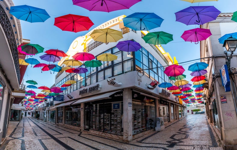 Photo of OLHAO, PORTUGAL - June 9th, 2019: Mixed varied colored umbrella decoration through the streets of downtown Olhao city.