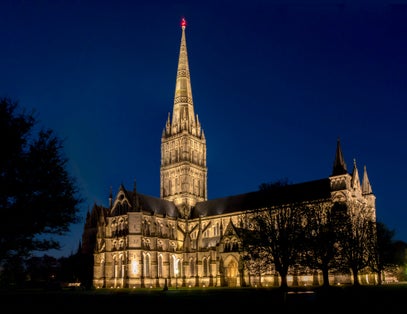 Photo of Salisbury Cathedral illuminated at night, formally known as the Cathedral Church of the Blessed Virgin Mary, an Anglican cathedral in Salisbury, England.