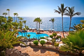 photo of aerial shot of Costa Adeje area, South Tenerife, Spain. Captured at golden hour, warm and vivid sunset colors. Luxury hotels, villas and restaurants behind the beach.