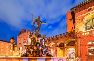 Photo of Italy Piazza Maggiore in Bologna old town tower of town hall with big clock and blue sky on background, antique buildings terracotta galleries.