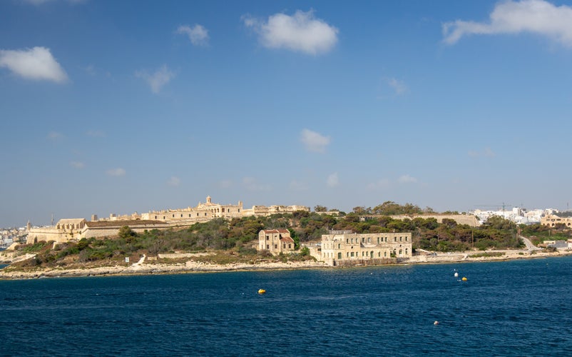 photo of view of Fort Manoel on Manoel Island in Gżira, Malta view from a distance with bright blue sky with a modern city in the background