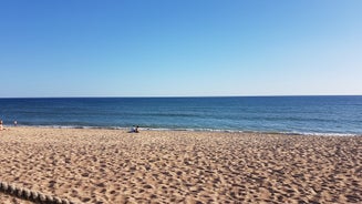 Photo of wide sandy beach in white city of Albufeira, Algarve, Portugal.