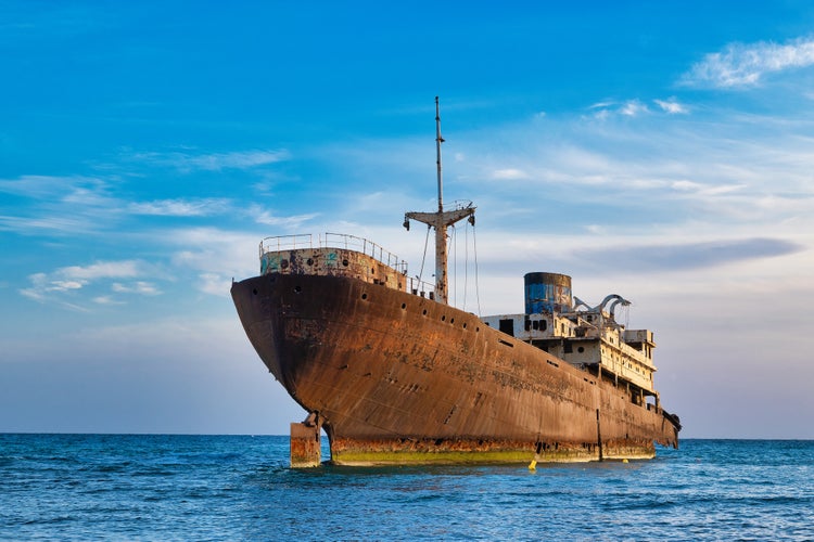 Photo of old wrecked ship in blue ocean, in the town of Arrecife on the island of Lanzarote, Canary Islands, Spain.