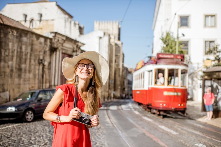 A young woman traveler standing on the street with famous tourist tram on the background in Lisbon, Portugal.jpg