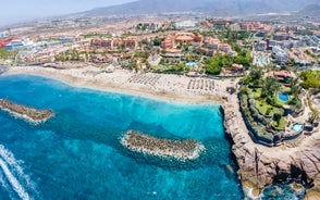 photo of aerial shot of Costa Adeje area, South Tenerife, Spain. Captured at golden hour, warm and vivid sunset colors. Luxury hotels, villas and restaurants behind the beach.