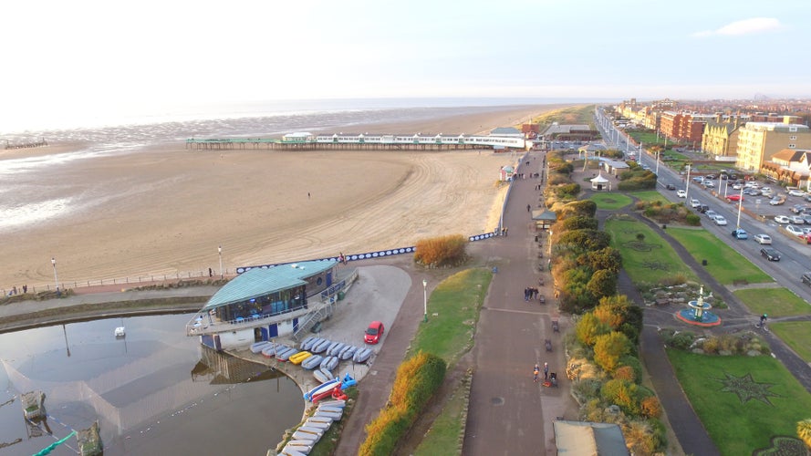 photo of view of St Annes on the Sea beach and boating lake, with the pier in the background, shot on a drone. The fylde coastline is shown in the sunlight.