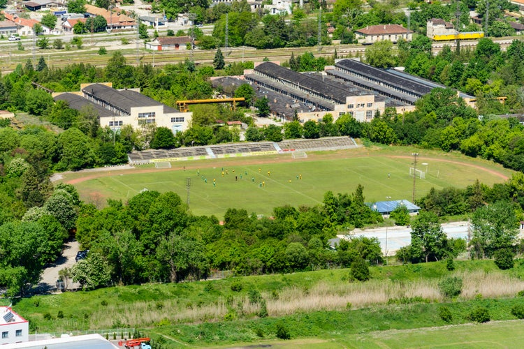 photo of aerial view of the Provadia football stadium with players , surrounded by warehouses in Bulgaria.