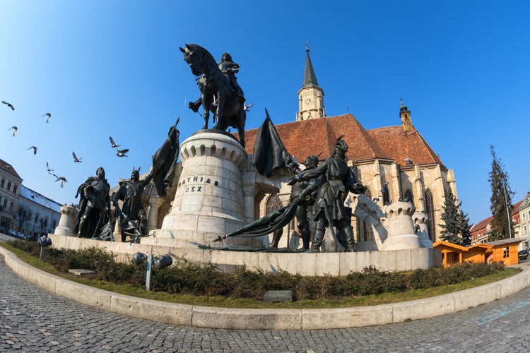 Doves flying over the statue of mathias rex in unirii square, cluj-napoca.