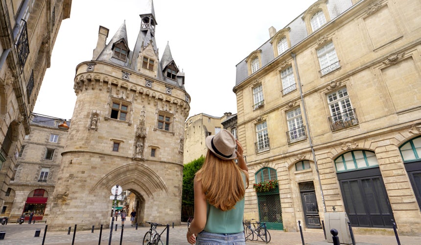 Tourism in Bordeaux, France. Traveler girl walking in Bordeaux discovering Porte Cailhau a medieval gatehouse of the old city walls.jpg