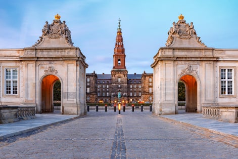 Photo of the main entrance to Christiansborg with the two Rococo pavilions on each side of the Marble Bridge during morning blue hour, Copenhagen, capital of Denmark.