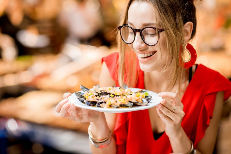 Woman eating mussels at the food market.jpg