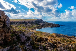 Photo of aerial view of seaside cliffs, colourful houses and streets of Qawra town in St. Paul's Bay area in the Northern Region, Malta.