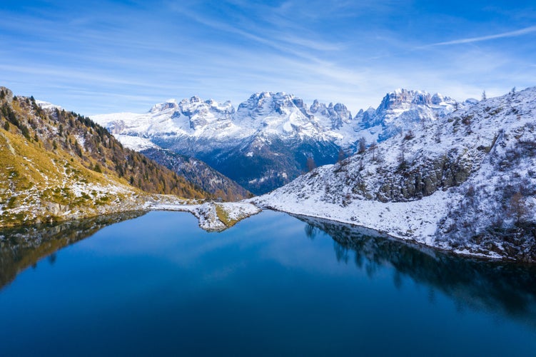 photo of clear mountain water reflecting the snowy peaks of the mountains in Ritorto Lake In Dolomites in Madonna di Campiglio in Italy.