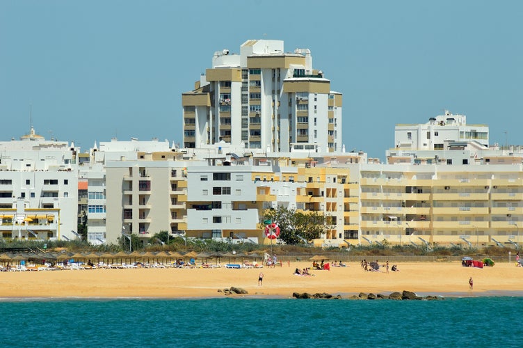 Photo of city buildings and clear blue sky background in Quarteira Beach, Algarve, Portugal.