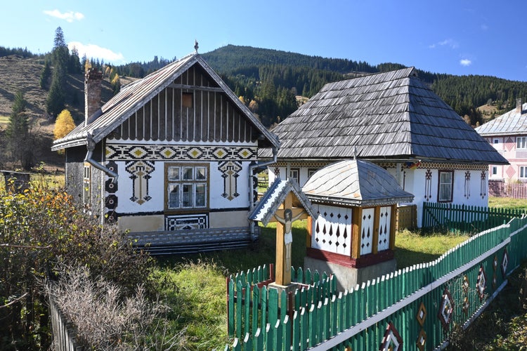 Trinity, fountain and traditional painted houses from Ciocanesti village, Suceava, Romania.