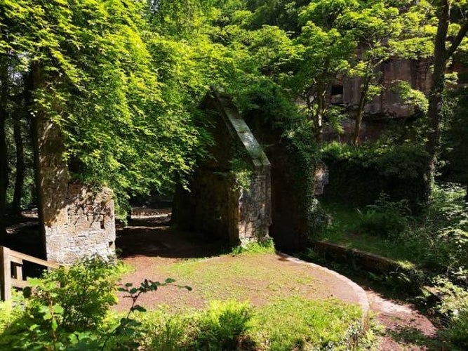 The moss-covered ruins of an old gunpowder factory hidden among the dense woodland of Roslin Glen, Scotland.jpg