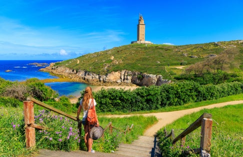 photo of woman tourist enjoying beautiful view of Hercules tower in La Coruna, Spain.