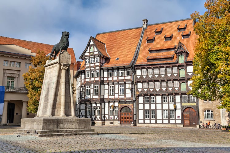 Photo of Statue of Lion and old half-timbered building on Burgplatz square in Braunschweig, Germany.