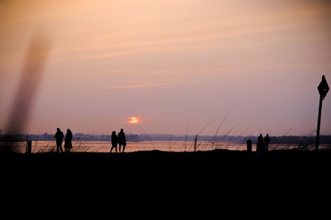 photo of A beautiful landscape of the sunset at the beach and people walking in Bull Island, Ireland
